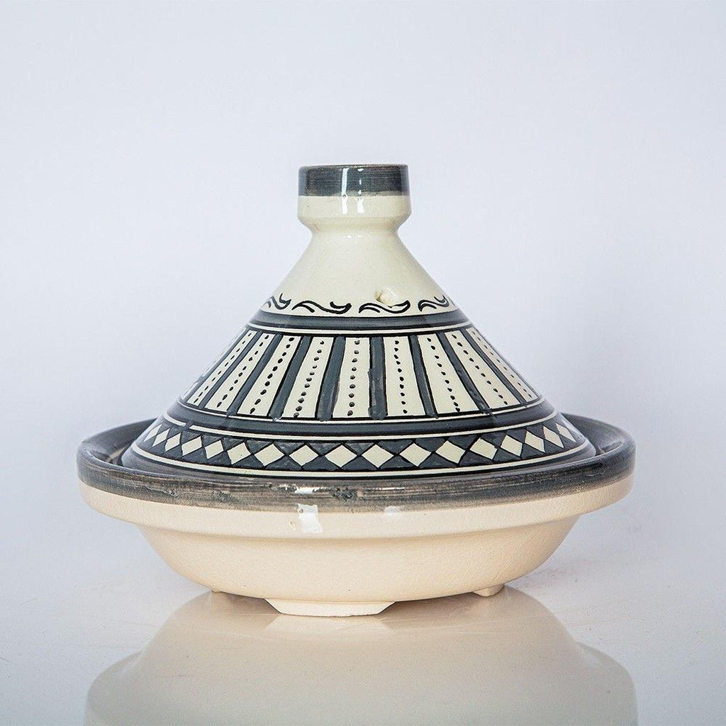 A decorative ceramic bowl with a patterned design on its surface, placed on a reflective surface against a plain background.