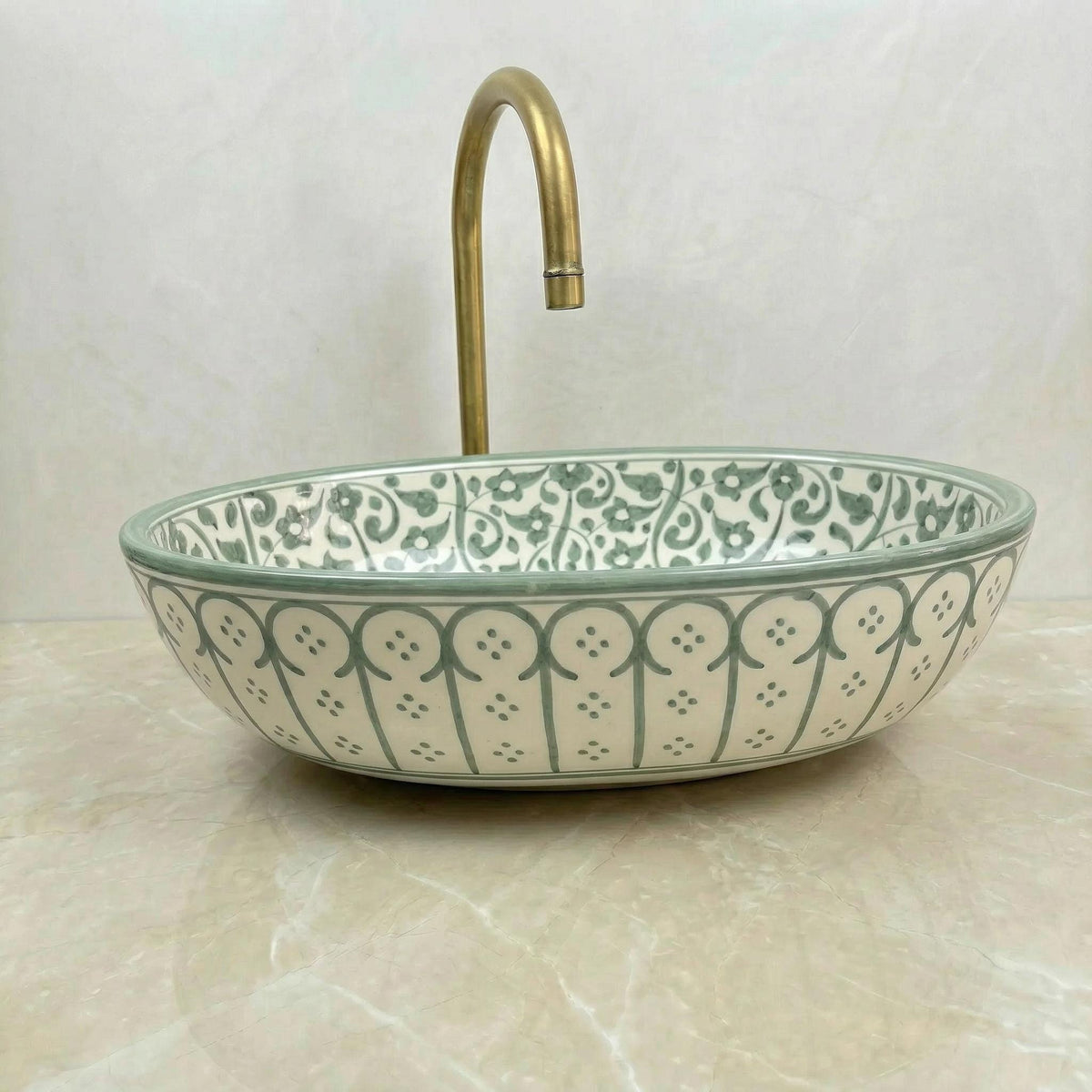 a decorative ceramic sink with a gold faucet, placed on a marble countertop.
