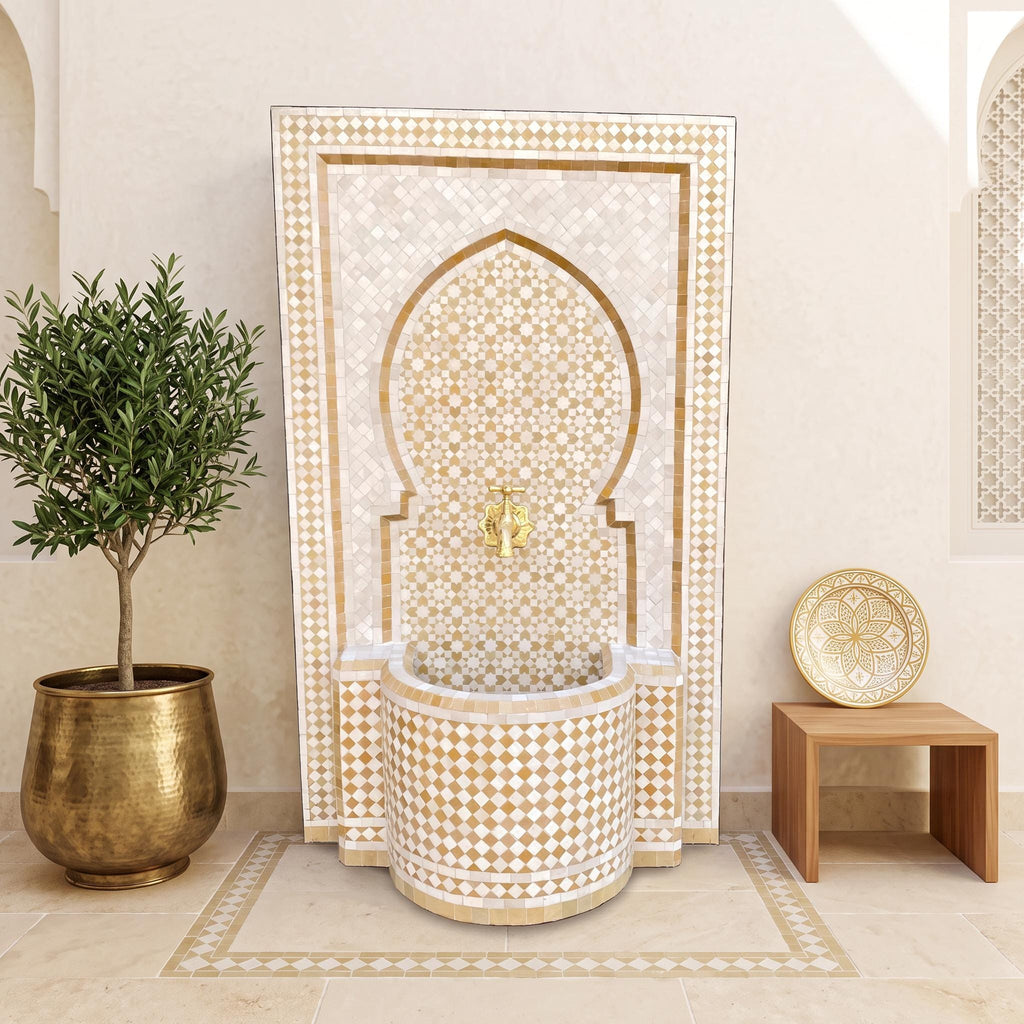 a luxurious bathroom with a large, ornate fountain adorned with gold and white tiles. The fountain is surrounded by a wooden table and a potted plant, creating a serene and elegant atmosphere.