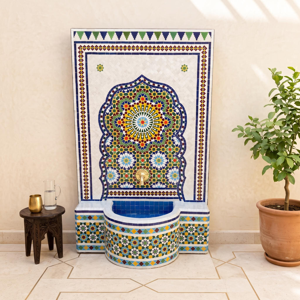 a colorful mosaic fountain with a blue and white base, surrounded by a potted plant and a small table.