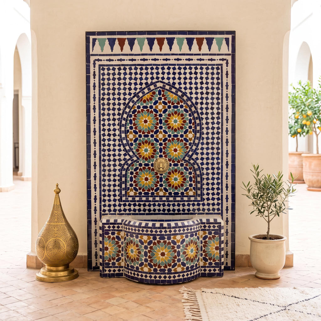 a decorative tile fountain with a blue and white mosaic design, situated in a hallway with a tiled floor. The fountain is surrounded by potted plants and a golden object, creating an elegant and visually appealing scene.