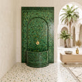 a modern bathroom with a green mosaic tile wall, a green mosaic tile fountain, and a wooden table with a decorative bowl on it.