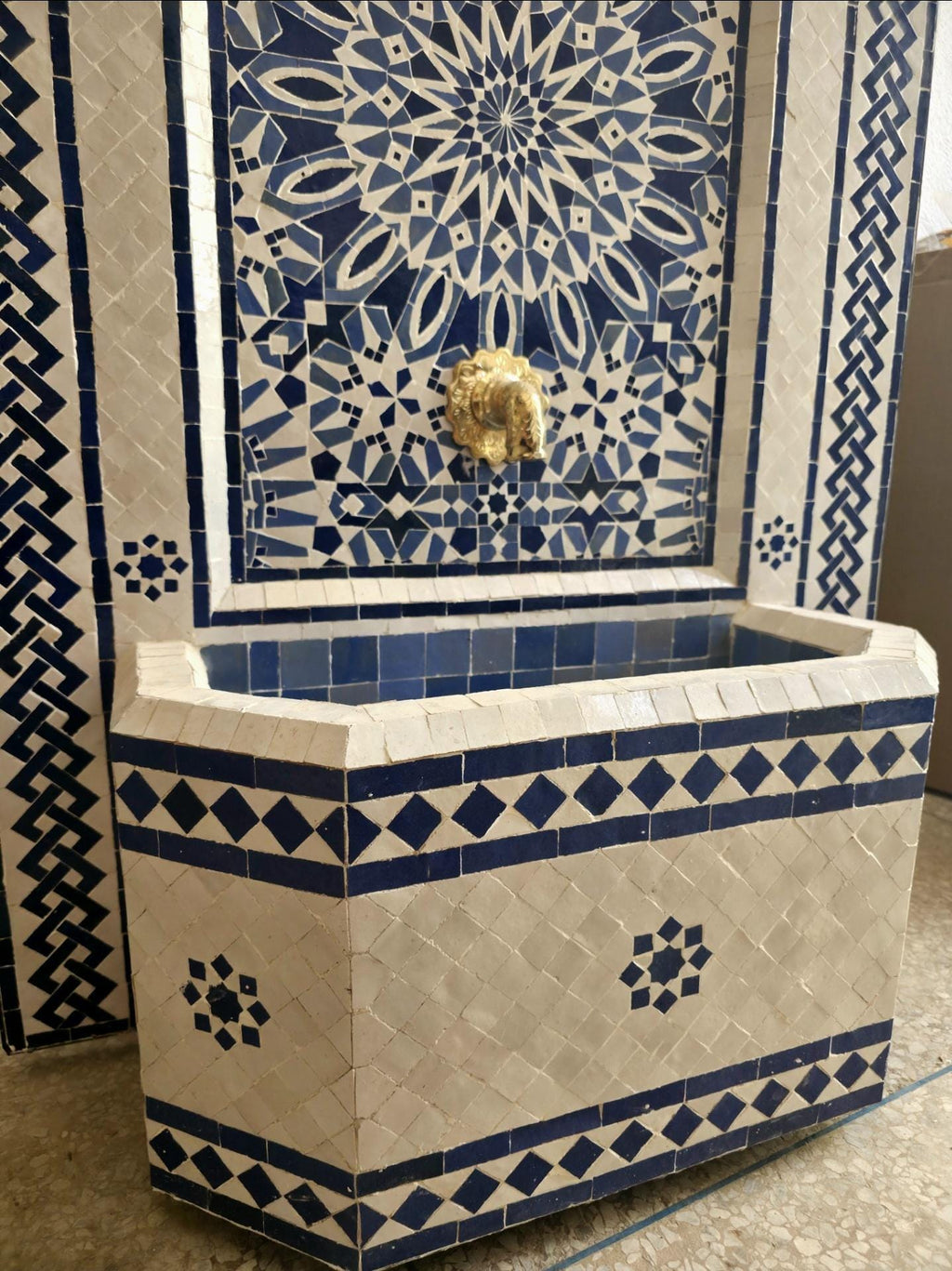 Close up of the central mosaic detail, showing an intricate sixteen point star rosette hand cut from cobalt blue, sky blue, and white zellige tiles.