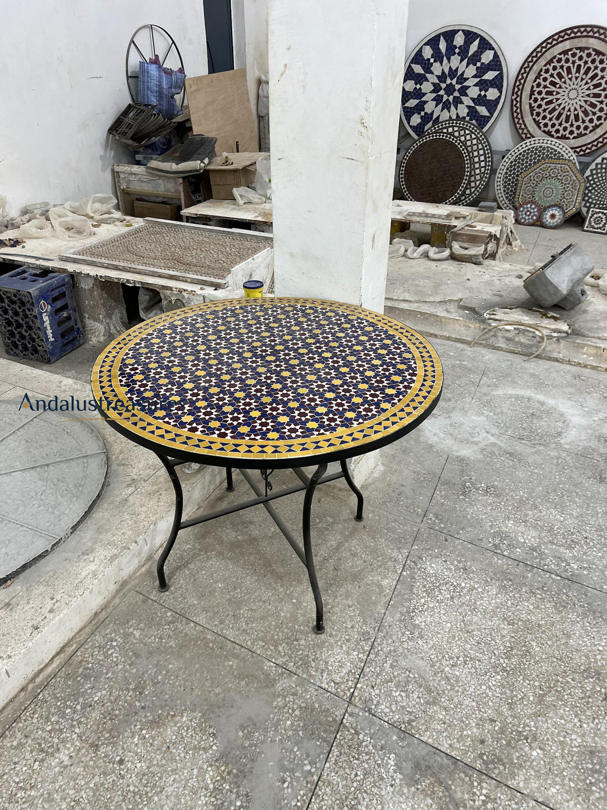 a table with a decorative tile top, surrounded by various decorative plates and bowls on display.