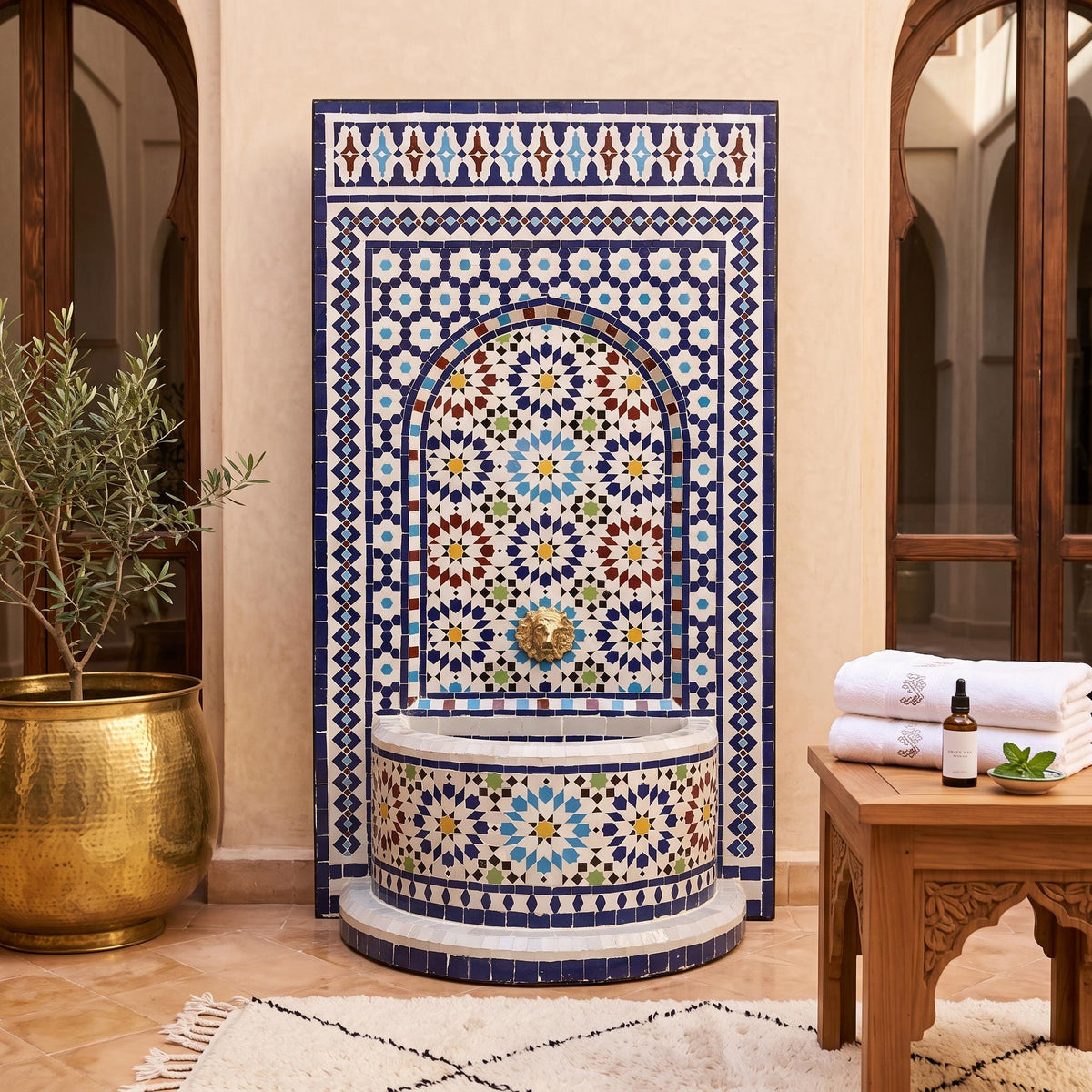 a decorative tile fountain with a blue and white mosaic design, situated in a room with a wooden table and a potted plant.