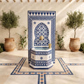 a decorative fountain with a blue and white tile design, surrounded by potted plants and a tiled floor.