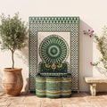 a decorative fountain with a green and white mosaic design, surrounded by potted plants and a stone bench.