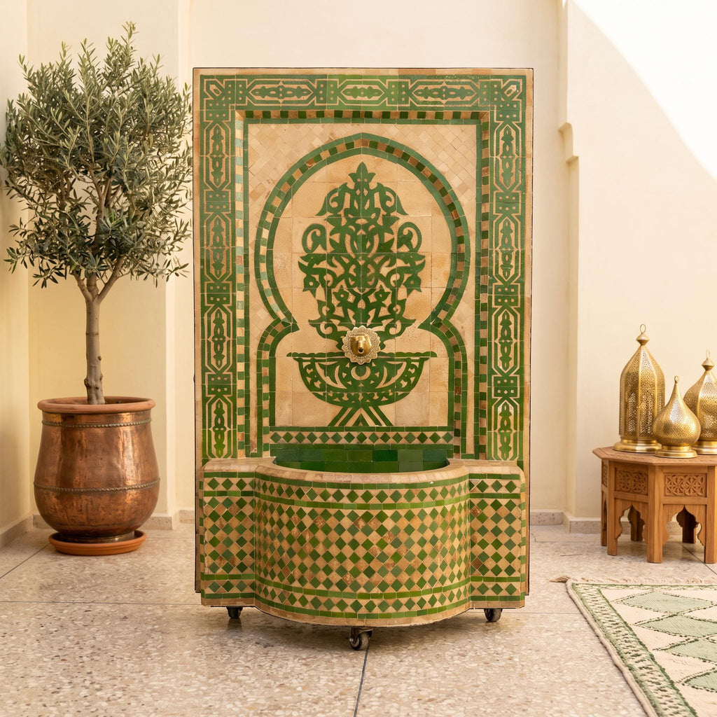 a decorative fountain with a green and gold mosaic design, situated in a room with a potted plant and other decorative elements.