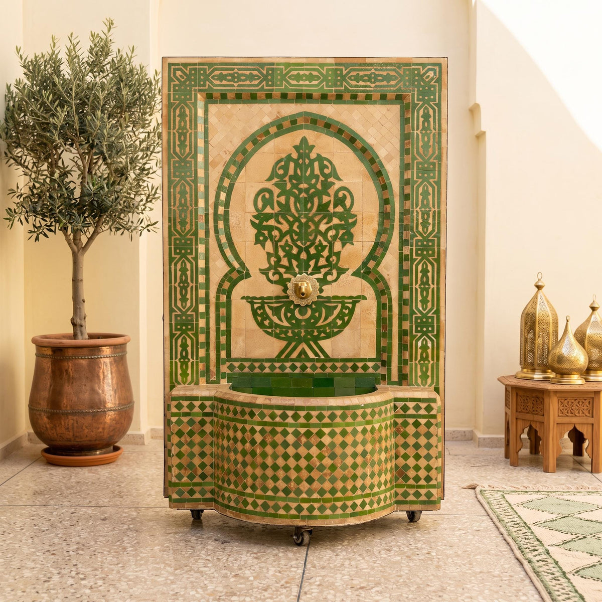 a decorative fountain with a green and gold mosaic design, situated in a room with a potted plant and other decorative elements.