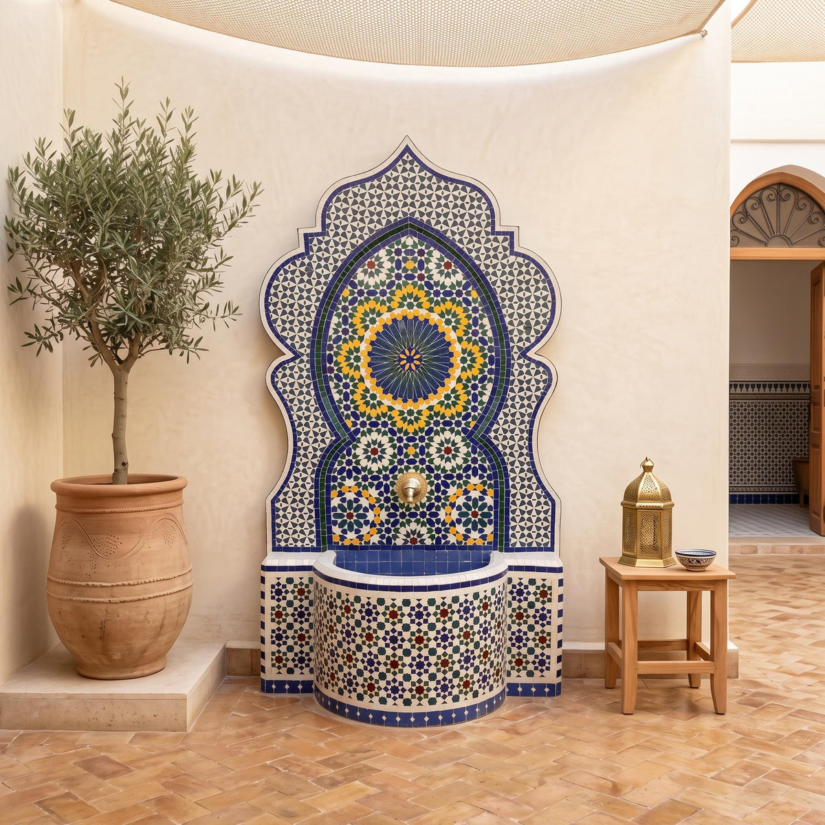 a decorative fountain with a mosaic design, surrounded by a potted plant and a small table with a bowl on it.