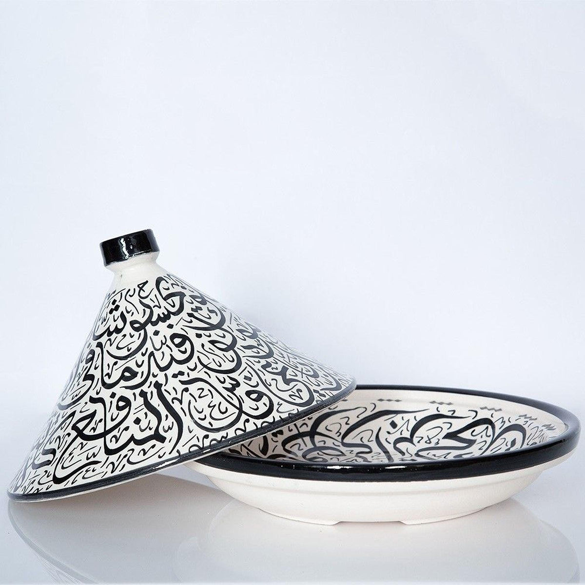 a decorative ceramic dish with a black and white pattern, placed on a white surface.