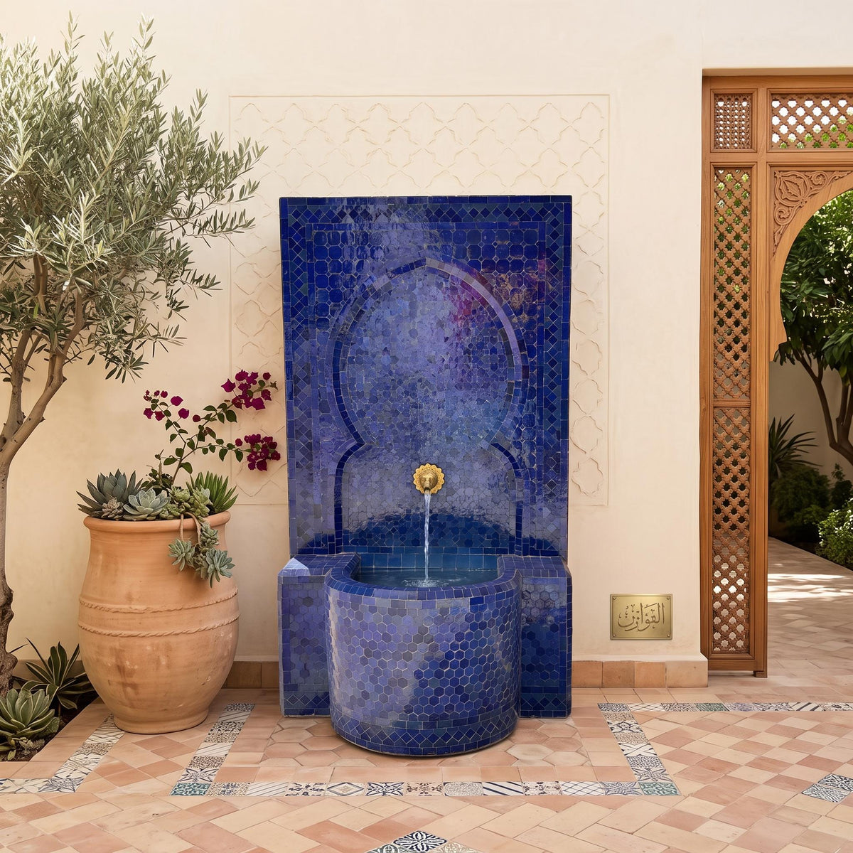 a blue mosaic fountain with a gold faucet, situated in a courtyard with a wooden archway and potted plants.