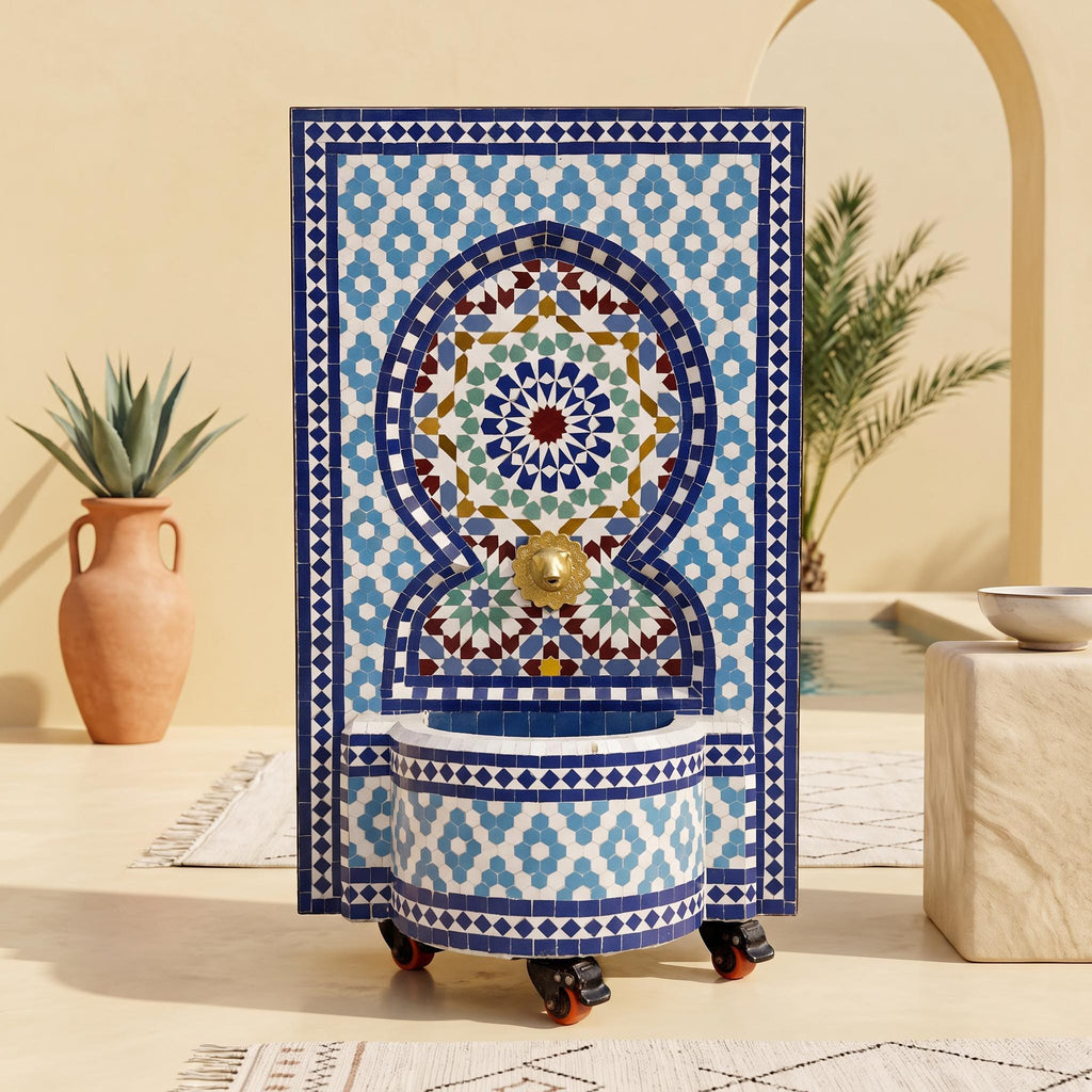 a decorative tile fountain with a blue and white geometric pattern, placed on a tiled floor. In the background, there is a potted plant and a bowl, creating a cozy and inviting atmosphere.