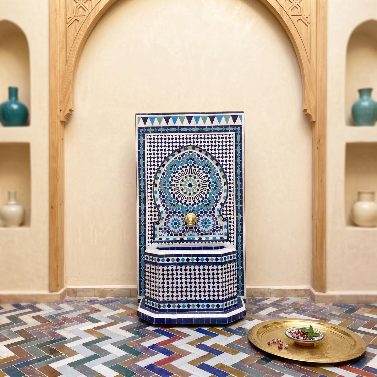 a decorative mosaic fountain with a blue and white pattern, situated in a room with arched doorways and shelves displaying vases.