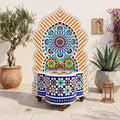 a decorative fountain with a colorful mosaic design, surrounded by potted plants and a lantern, creating a serene and inviting atmosphere.