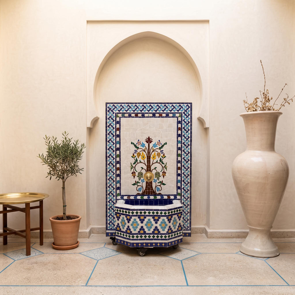 a decorative tile fountain with a blue and white border, situated in a room with a white archway. The room also includes a table with a plant and a large white vase.