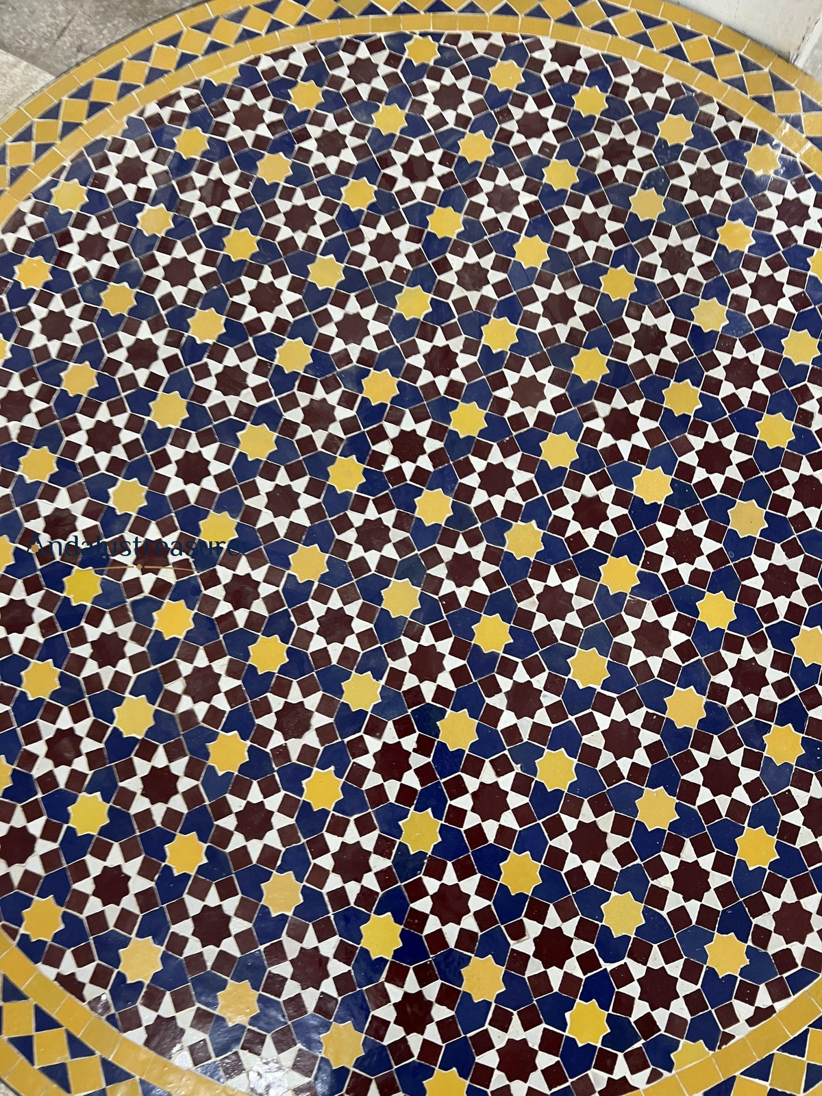 a circular tile floor with a geometric pattern of yellow and blue stars arranged in a repeating design.