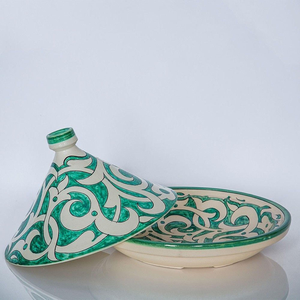 a decorative ceramic dish with a green and white pattern, placed on a white surface.