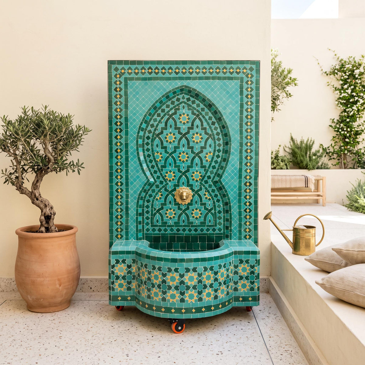 a decorative tile fountain with a green and gold pattern, placed on a tiled floor next to a potted plant and a watering can.