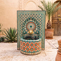 a decorative fountain with a mosaic design, surrounded by potted plants and a wooden door.