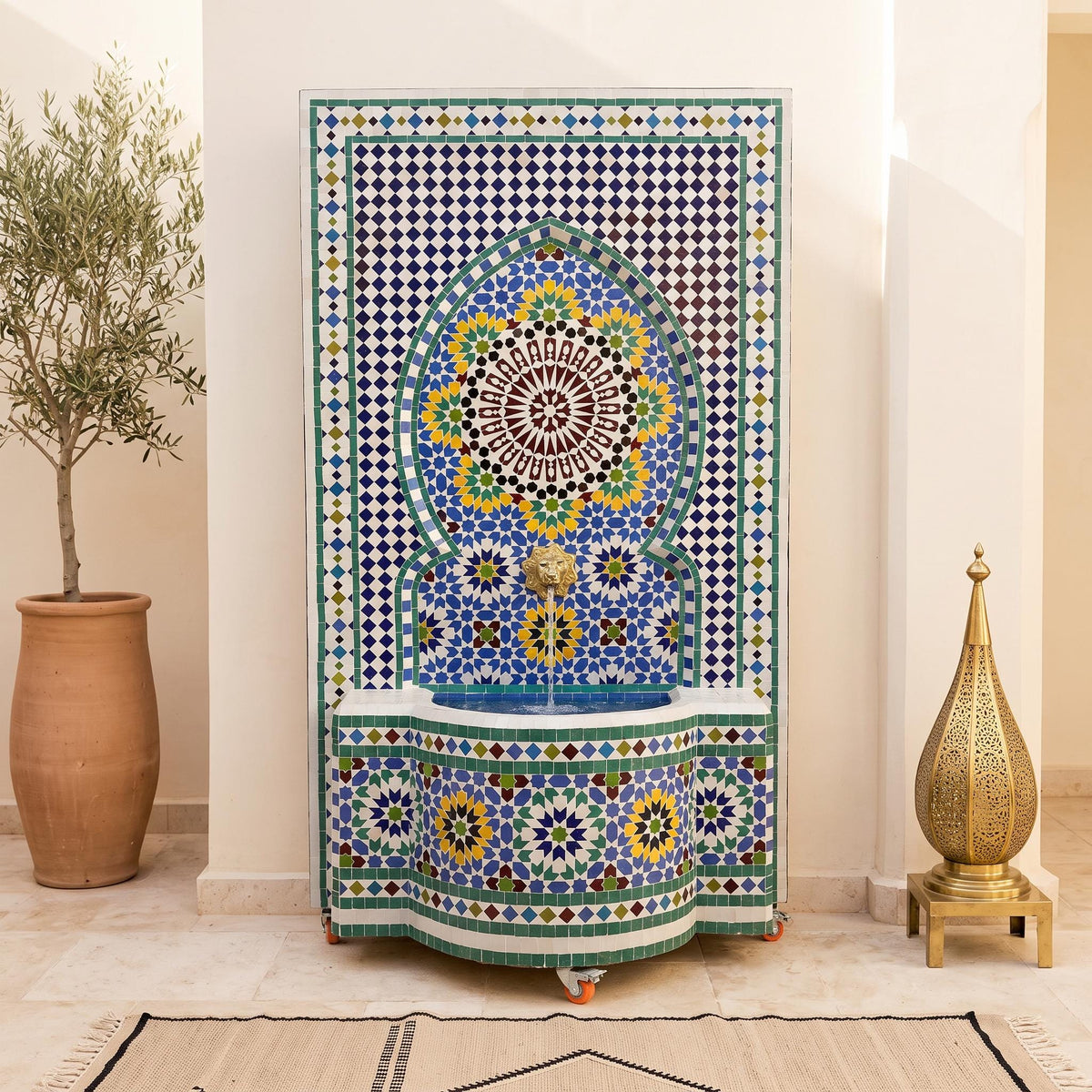 a decorative mosaic fountain with a blue and white tile design, situated in a room with a potted plant and a brass lamp.