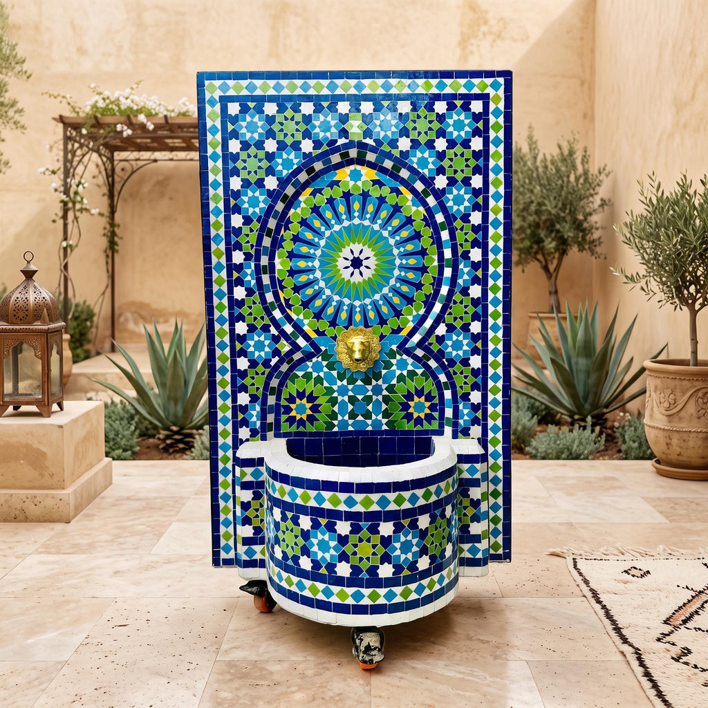 a decorative fountain with a mosaic design in blue, green, and white colors, situated in a courtyard surrounded by potted plants and a rug.