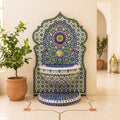 a decorative mosaic fountain with a blue and white pattern, situated in a room with a potted plant and a lantern.