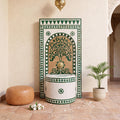 a decorative fountain with a tree-like design, surrounded by a tiled wall and a potted plant.