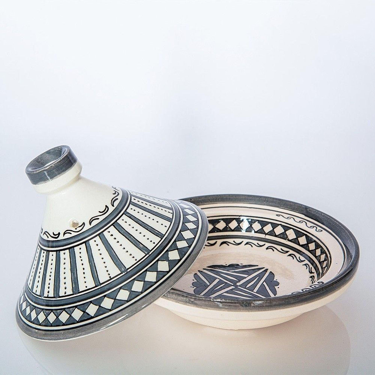 a white and black ceramic bowl with a decorative pattern on its surface, placed on a white surface.