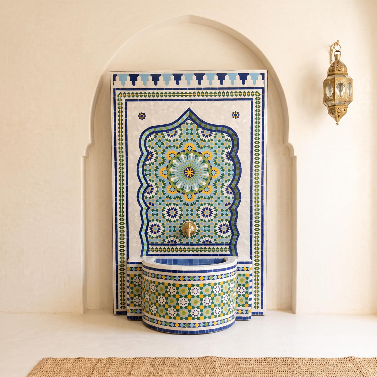 a decorative fountain with a mosaic design, situated in a room with a white wall and a gold-colored lamp.