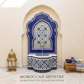 a beautifully crafted Moroccan-style fountain with intricate blue and white tile work, situated in a room with a wooden table and a gold lantern.